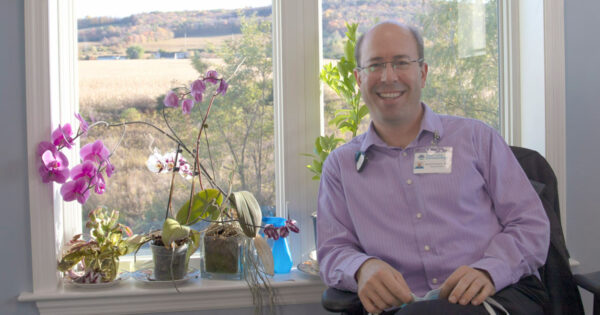 Brad Yentzer sitting in chair in Dermatologist office, in front of window with flowers in Dryden, NY
