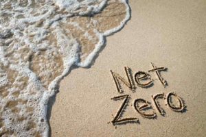 eco-friendly shoreline on beach with the words Net Zero written in the sand
